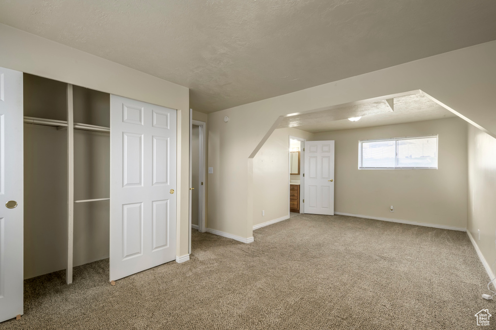 Unfurnished bedroom featuring a closet, baseboards, arched walkways, and carpet flooring