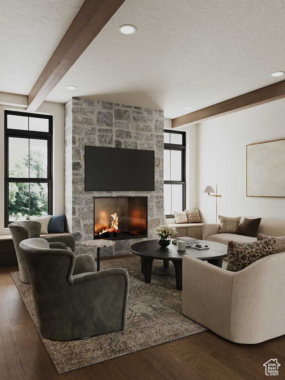 Living area with beam ceiling, wood finished floors, a stone fireplace, and a textured ceiling