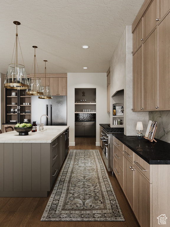 Kitchen featuring light brown cabinets, dark wood finished floors, a center island with sink, high quality appliances, and pendant lighting