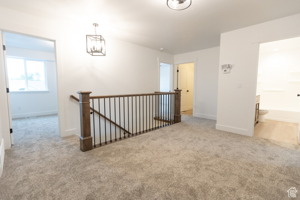 Carpeted spare room with baseboards and a chandelier