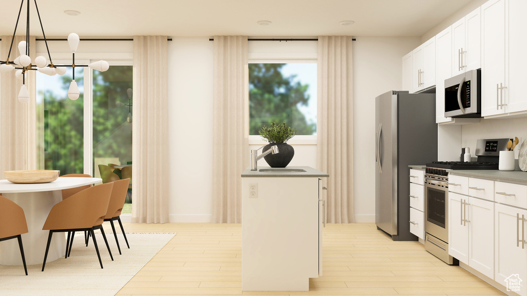 Kitchen with decorative light fixtures, appliances with stainless steel finishes, light wood-style floors, a notable chandelier, and white cabinetry