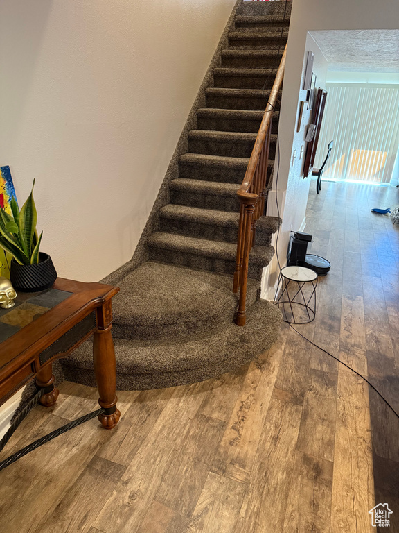 Staircase with wood-type flooring and a textured ceiling