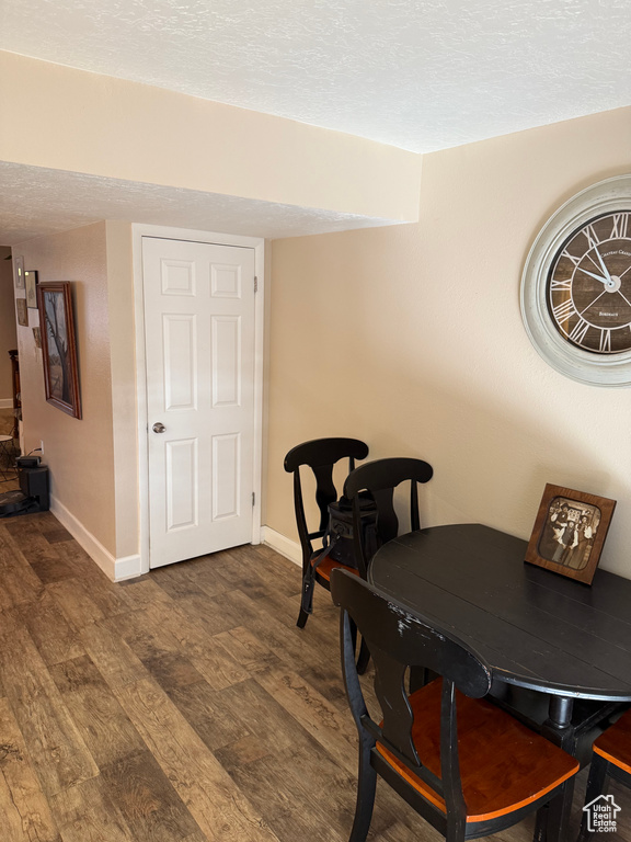 Dining space featuring baseboards, a textured ceiling, and wood finished floors