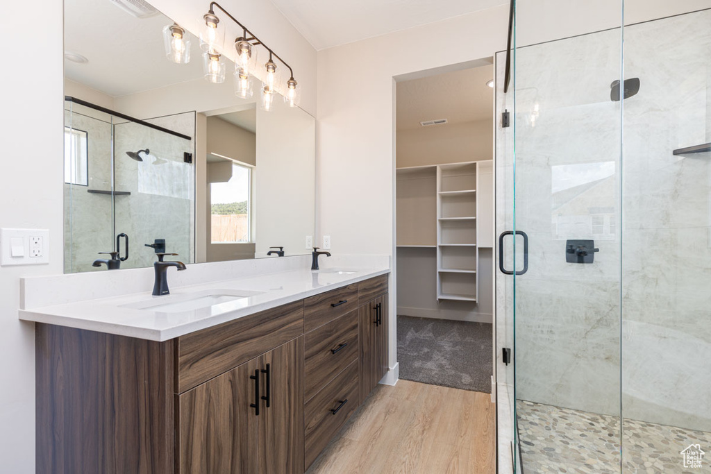 Full bathroom featuring wood finished floors, double vanity, and a stall shower