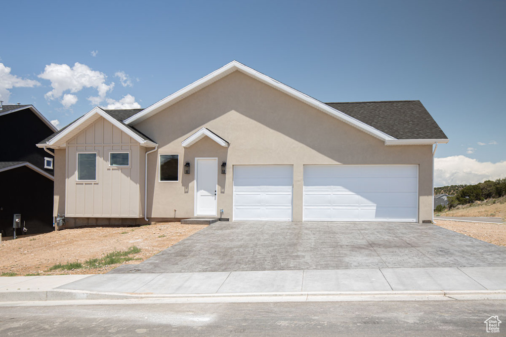 Ranch-style home with driveway, a garage, and board and batten siding