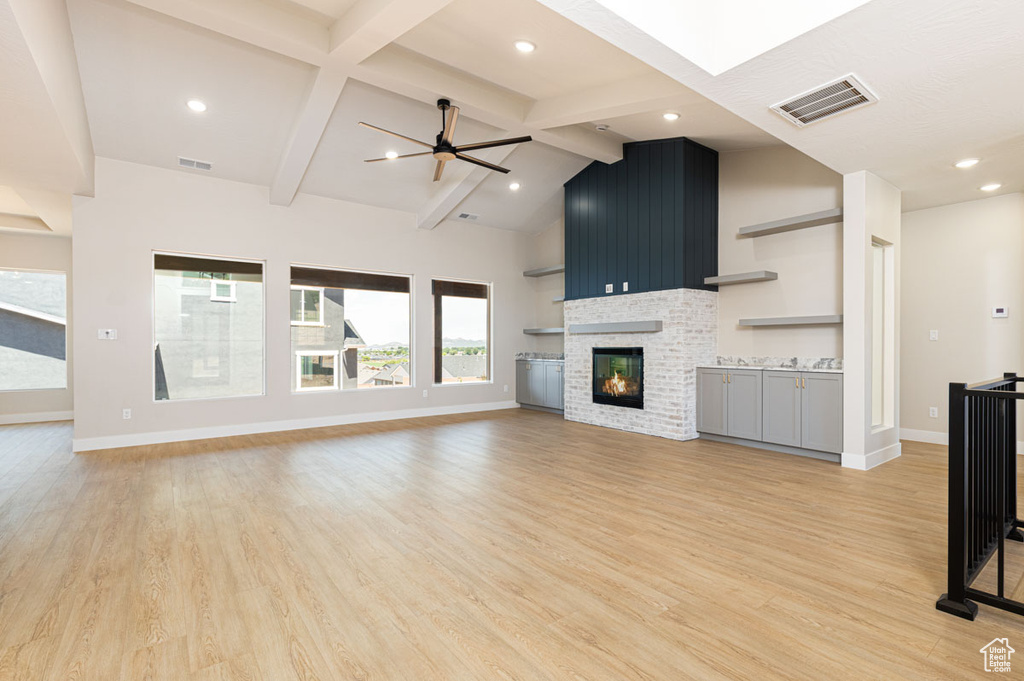 Unfurnished living room with light wood-style flooring, a glass covered fireplace, and recessed lighting