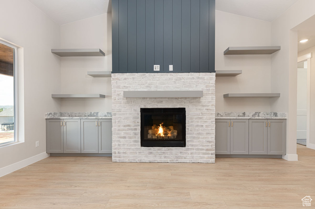 Unfurnished living room featuring lofted ceiling, light wood finished floors, and a fireplace