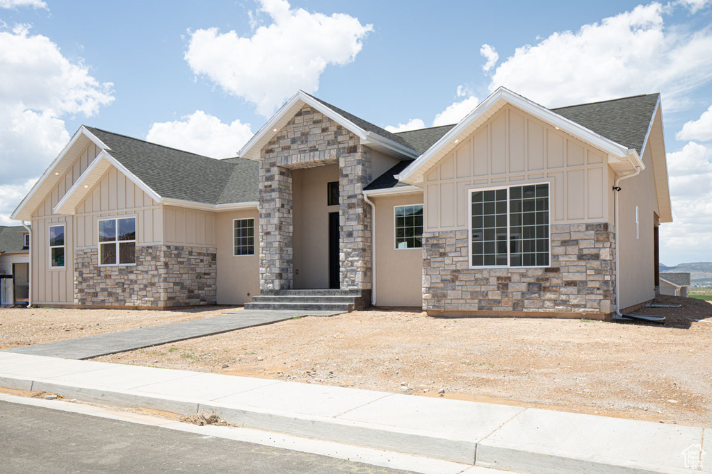 View of front of home with stone siding, board and batten siding, and a shingled roof