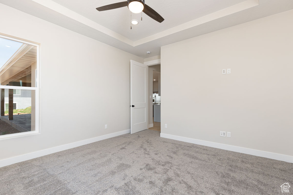 Unfurnished room with ceiling fan, carpet flooring, and a raised ceiling