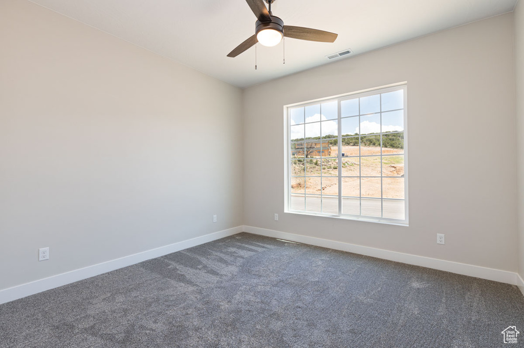 Spare room featuring dark carpet and ceiling fan