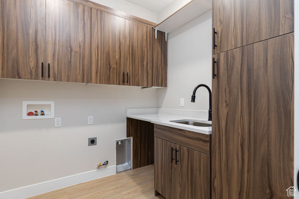 Laundry room featuring hookup for a gas dryer, cabinet space, hookup for an electric dryer, light wood-style flooring, and hookup for a washing machine
