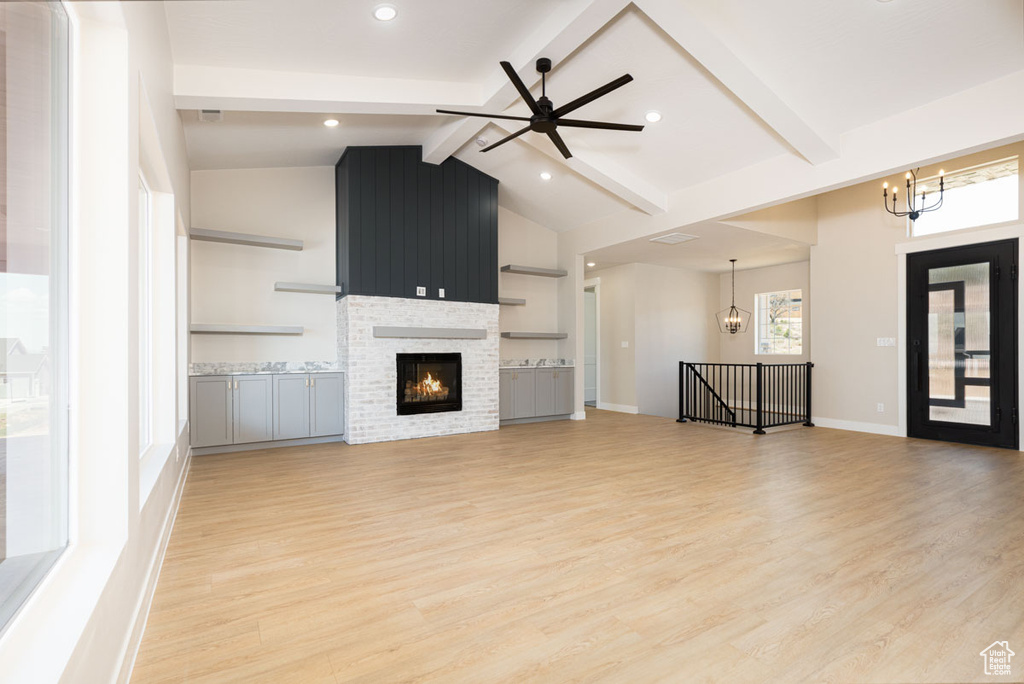 Unfurnished living room featuring a chandelier, light wood finished floors, ceiling fan, a fireplace, and recessed lighting