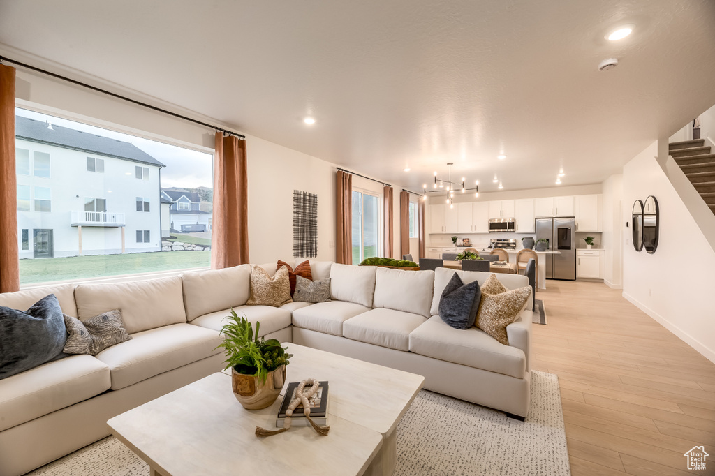 Living area featuring recessed lighting, stairway, light wood finished floors, baseboards, and a chandelier