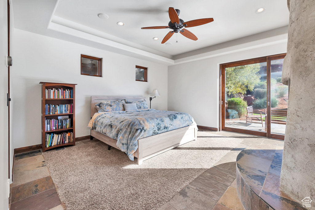 Bedroom featuring stone tile floors, a tray ceiling, and access to outside