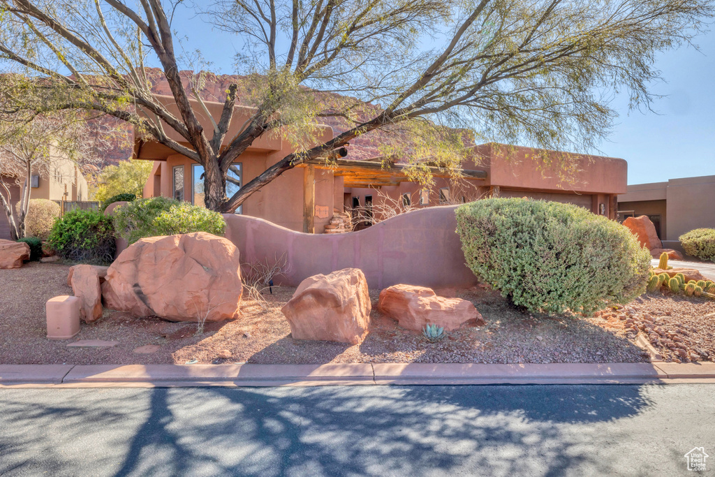 Pueblo-style house featuring a fenced front yard and stucco siding
