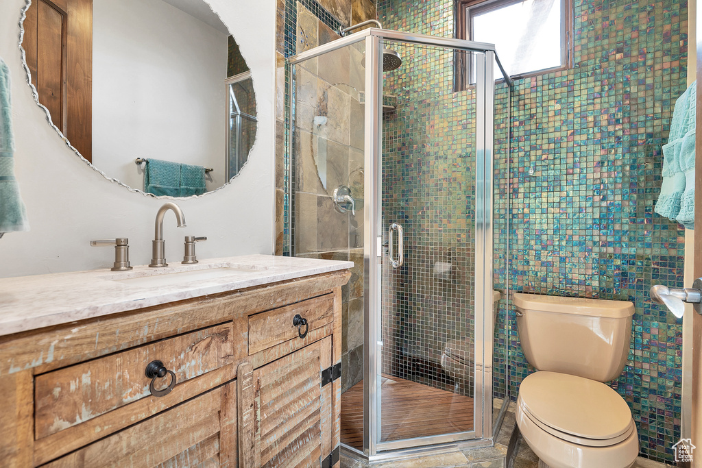 Bathroom with vanity, a shower stall, and toilet