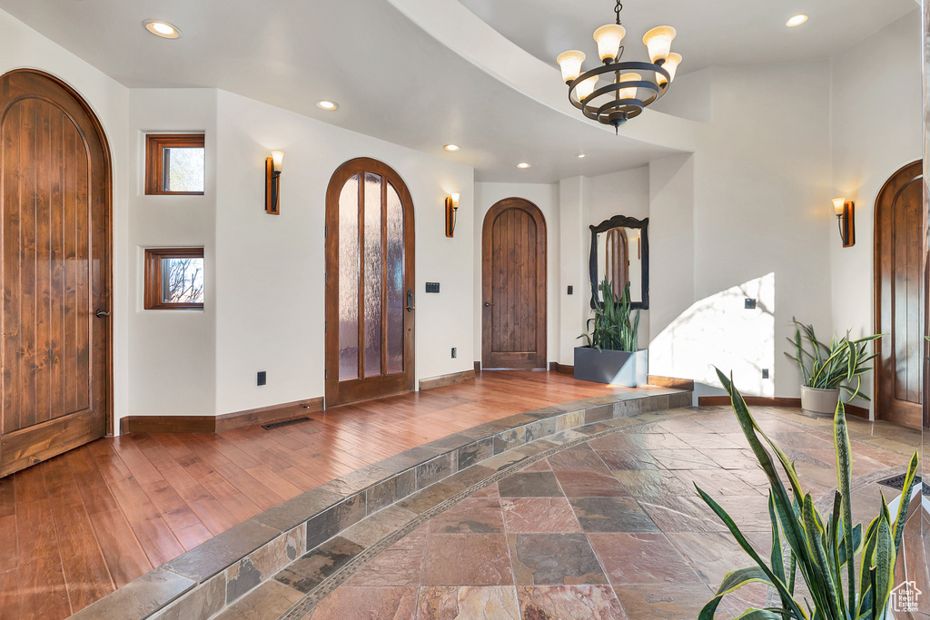 Entryway featuring baseboards, recessed lighting, arched walkways, a notable chandelier, and wood-type flooring