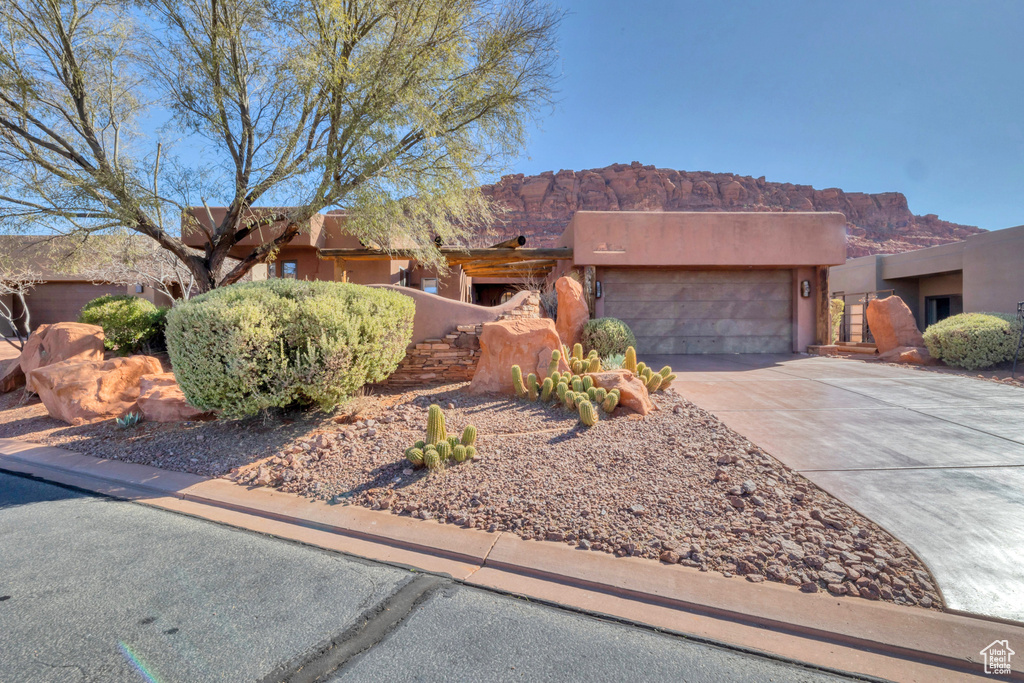 Southwest-style home with concrete driveway, an attached garage, and a mountain view