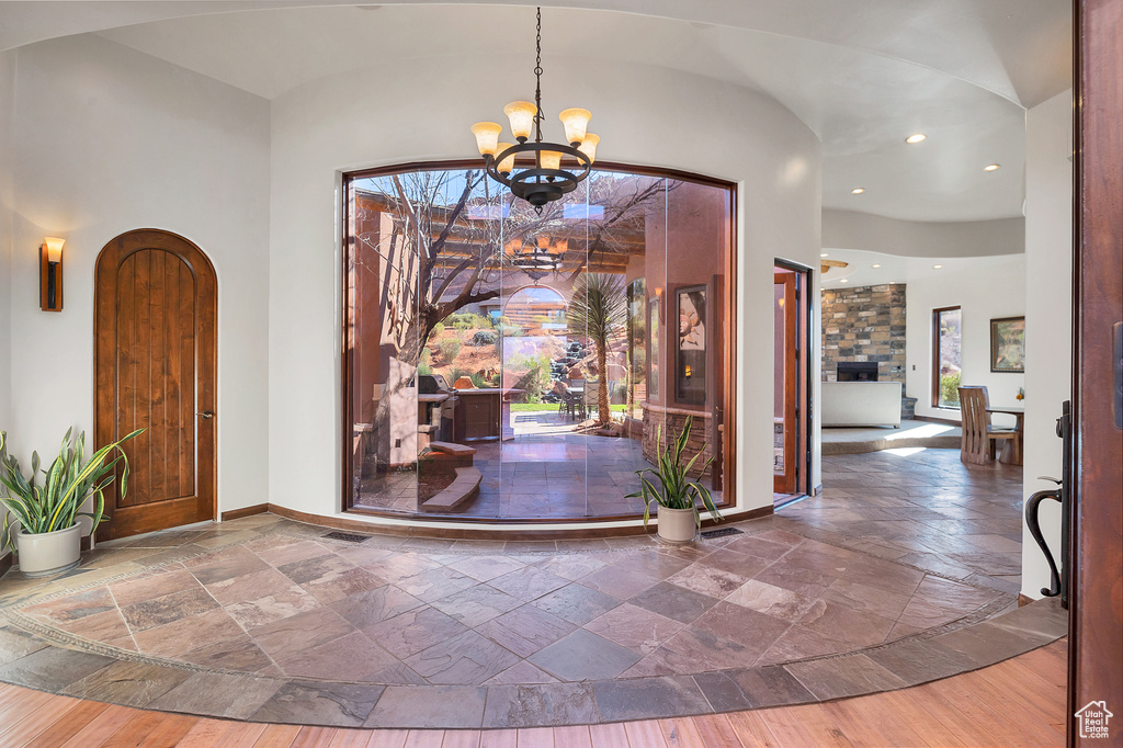 Entrance foyer with stone tile floors, a notable chandelier, baseboards, and plenty of natural light