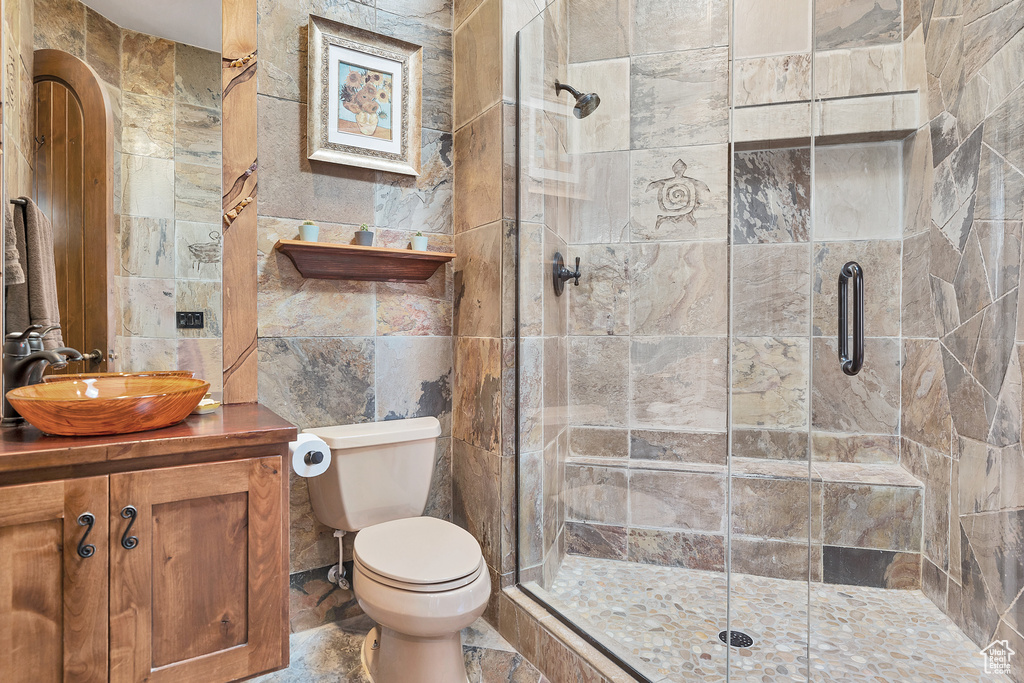 Full bath with a shower stall, toilet, and tile walls