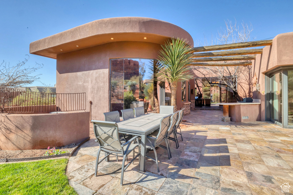 View of patio with an outdoor kitchen, outdoor dining area, and fence