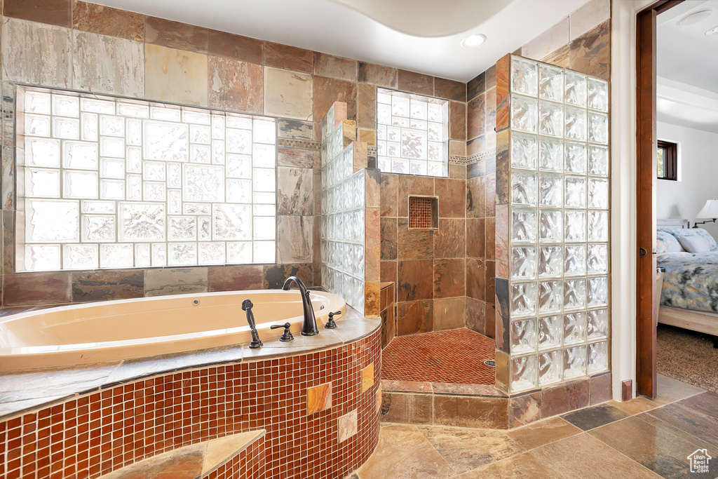 Bathroom featuring stone tile floors, a bath, a walk in shower, and connected bathroom