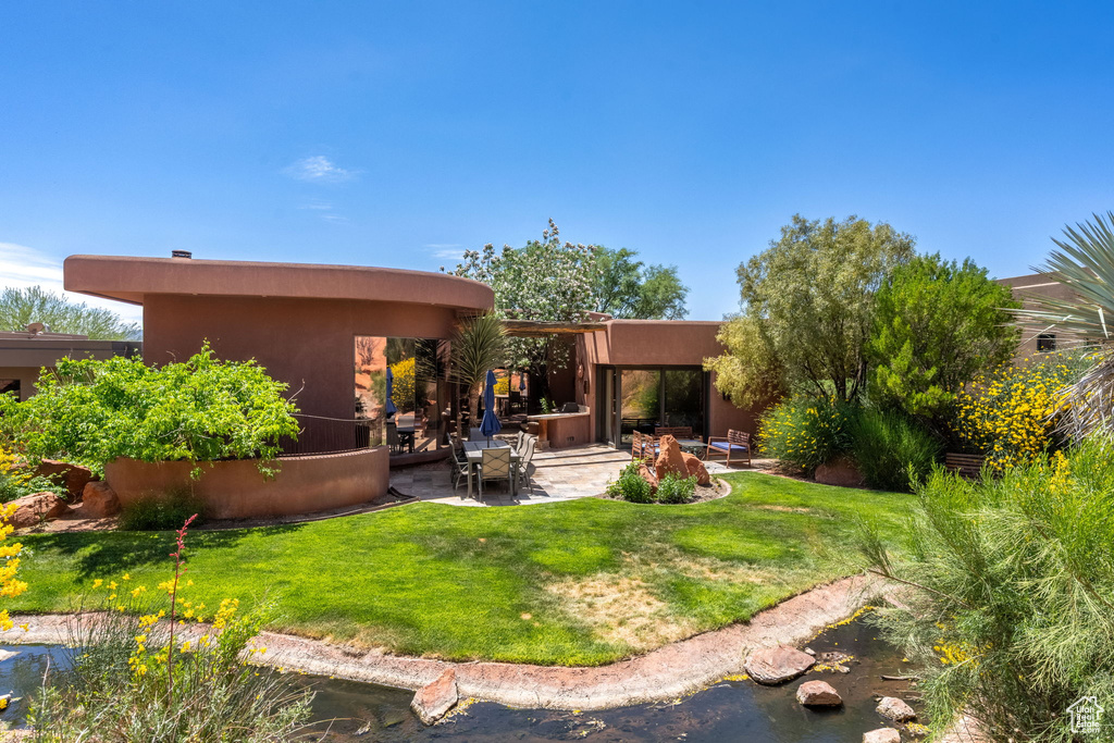 Back of property featuring a patio area, stucco siding, and a yard