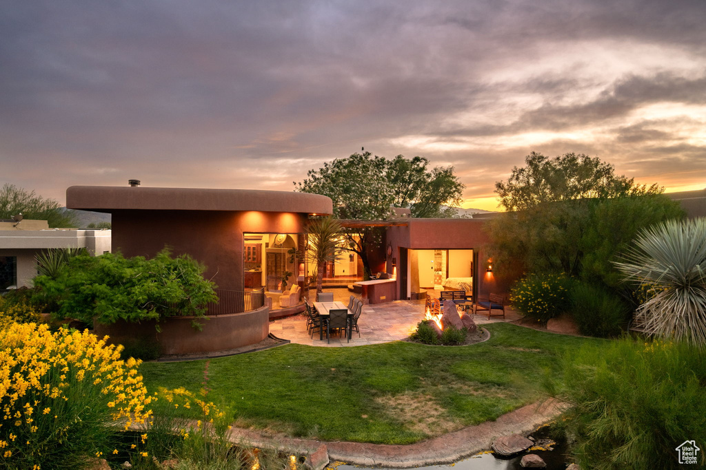 Rear view of house featuring a patio, a yard, and stucco siding