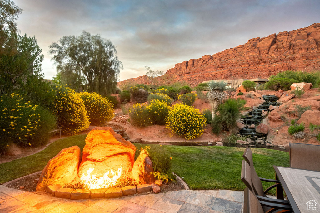 Yard at dusk featuring a yard, a mountain view, and an outdoor fire pit
