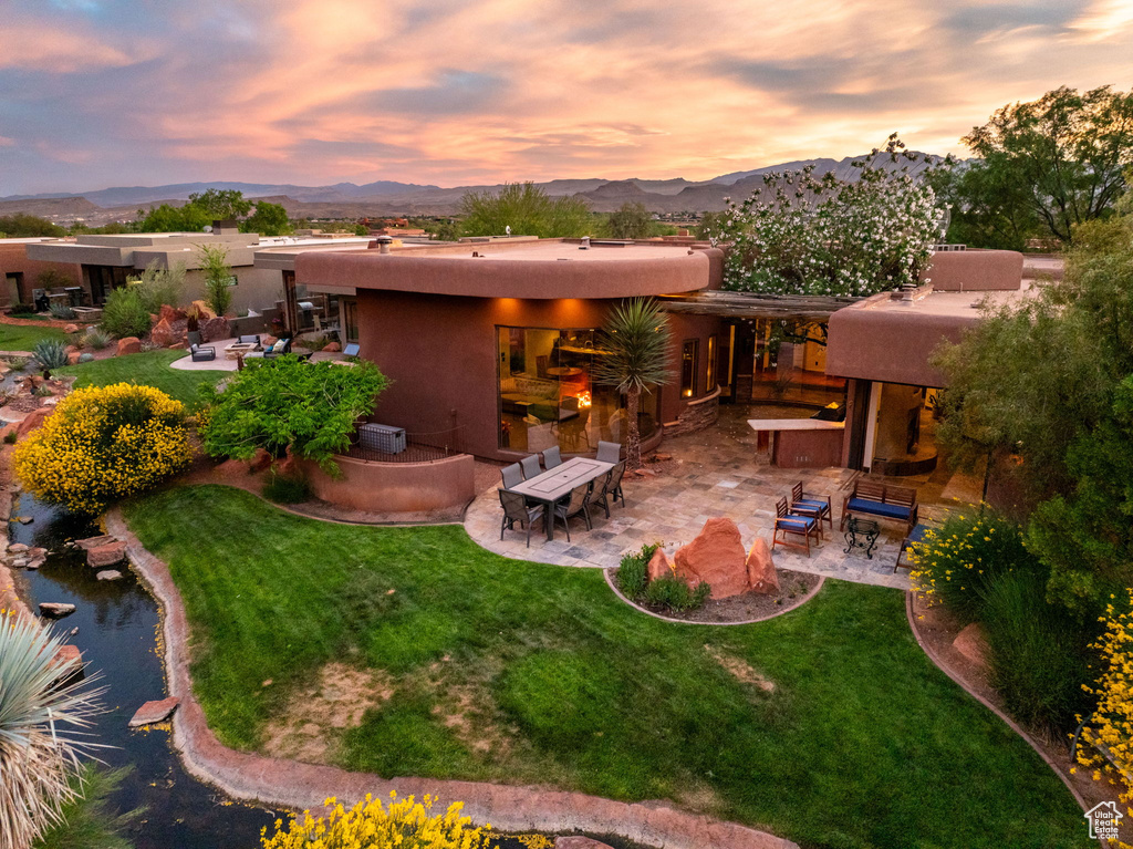 Back of house at dusk with a patio area, stucco siding, and a mountain view