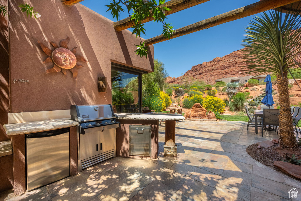 View of patio with an outdoor kitchen, outdoor dining space, a mountain view, and area for grilling