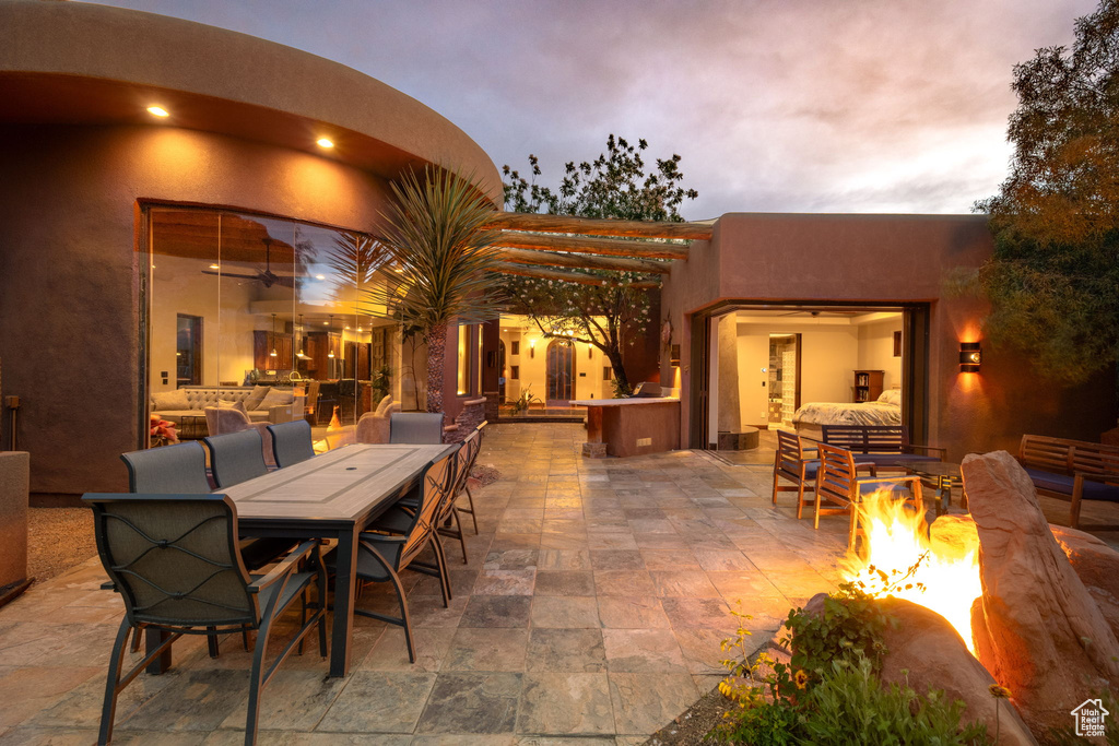 Patio terrace at dusk featuring an outdoor fire pit, outdoor dining space, and area for grilling