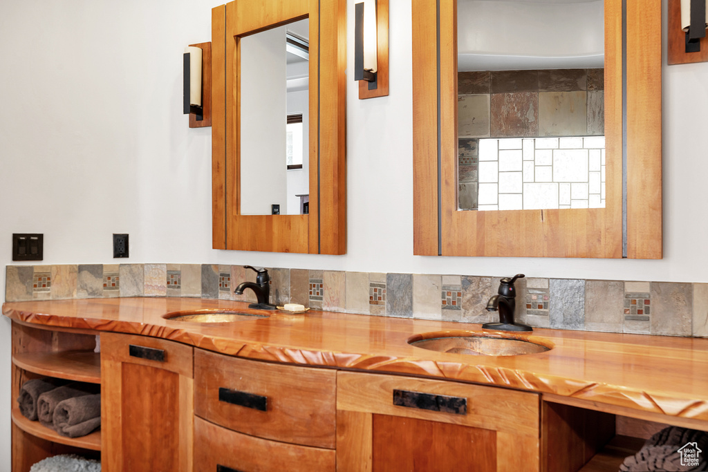 Bathroom featuring decorative backsplash, double vanity, and a sink
