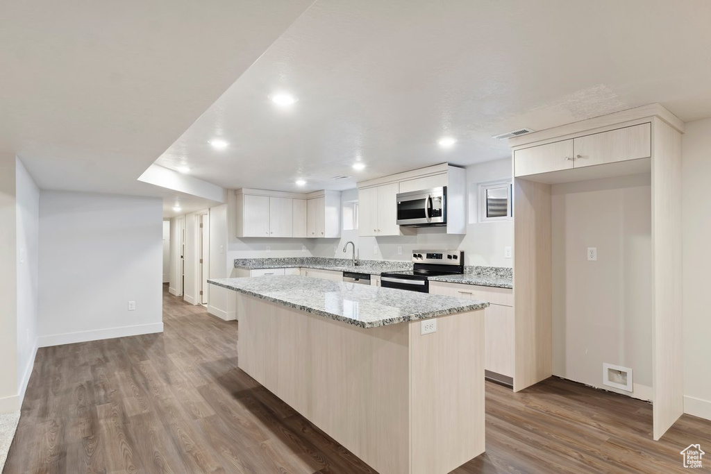 Kitchen with visible vents, wood finished floors, a center island, white cabinetry, and appliances with stainless steel finishes