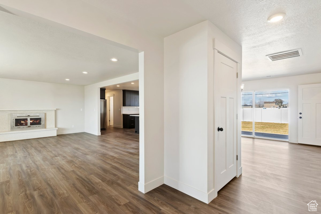 Unfurnished living room featuring visible vents, baseboards, a textured ceiling, and dark wood finished floors