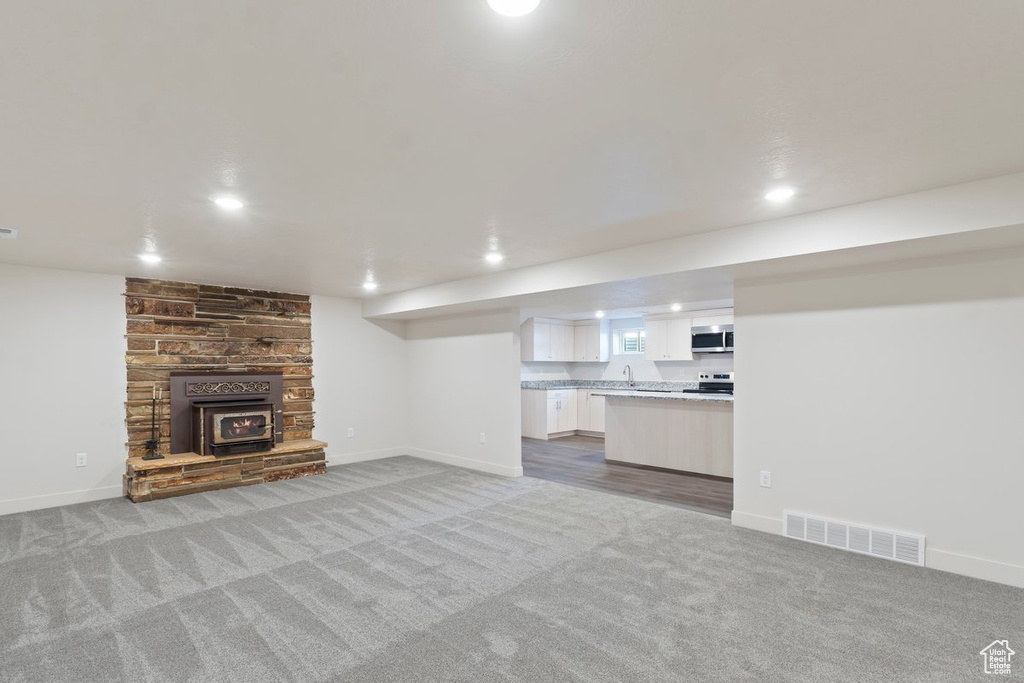 Unfurnished living room featuring visible vents, baseboards, light carpet, a stone fireplace, and recessed lighting