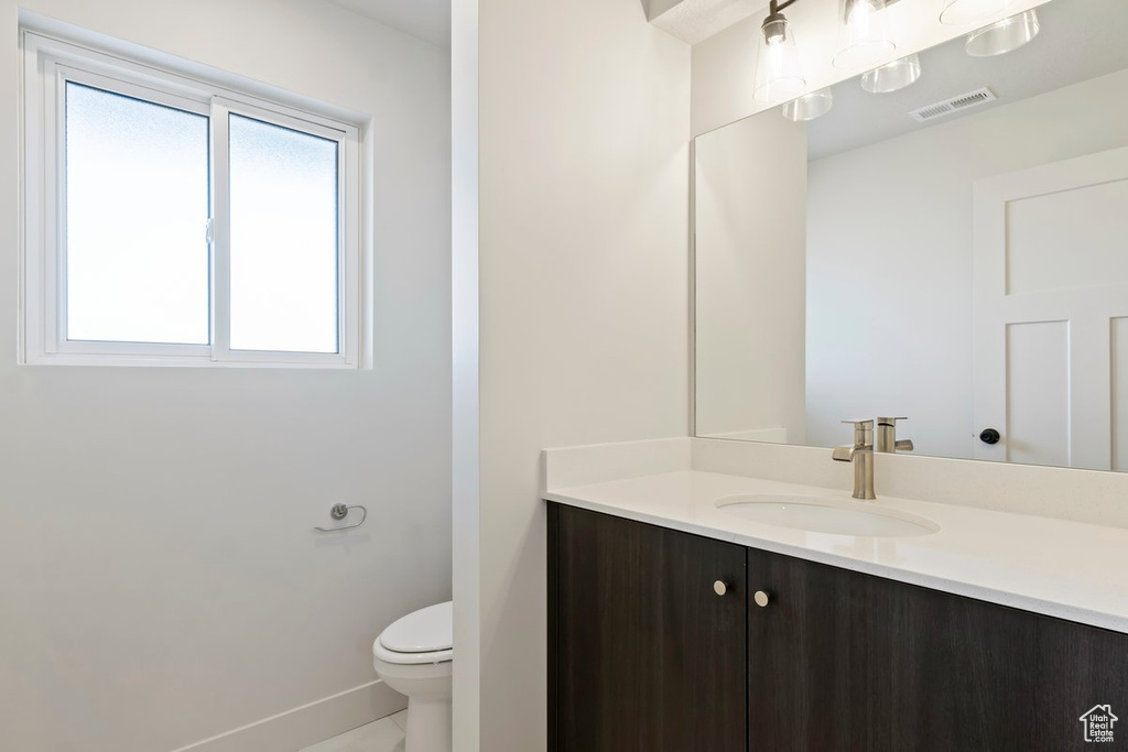 Bathroom featuring visible vents, baseboards, toilet, and vanity