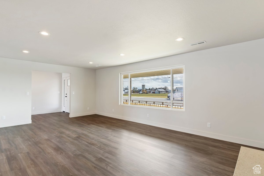 Spare room featuring dark wood-type flooring, recessed lighting, baseboards, and visible vents