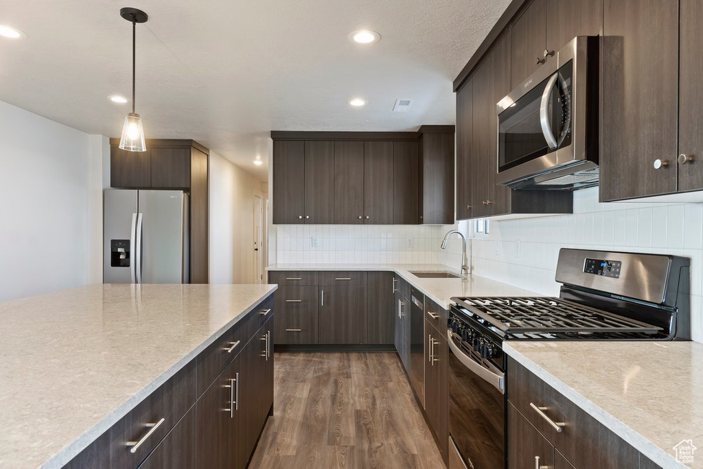 Kitchen featuring dark brown cabinetry, appliances with stainless steel finishes, light countertops, and a sink