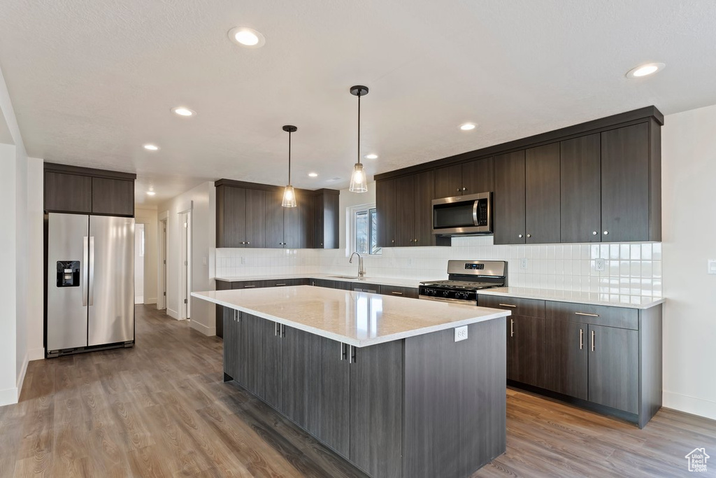 Kitchen featuring a center island, dark brown cabinetry, stainless steel appliances, and light wood-type flooring