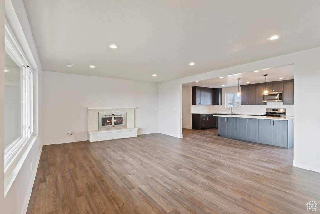Unfurnished living room with a sink, recessed lighting, baseboards, and wood finished floors