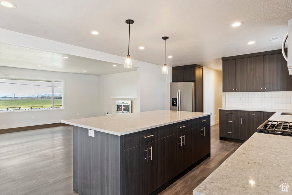 Kitchen with backsplash, a kitchen island, dark wood-type flooring, recessed lighting, and stainless steel refrigerator with ice dispenser