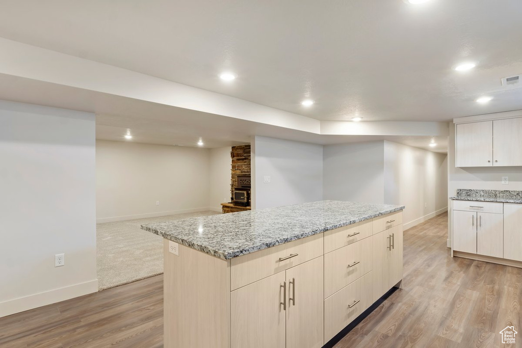 Kitchen with light stone counters, baseboards, light wood-style flooring, recessed lighting, and a center island