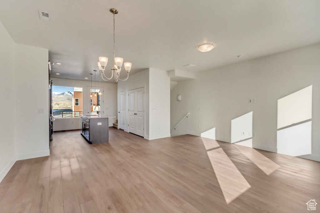 Interior space with a notable chandelier, baseboards, visible vents, and light wood-type flooring