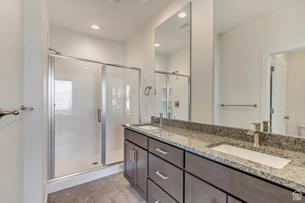 Full bathroom with a sink, toilet, a stall shower, and double vanity