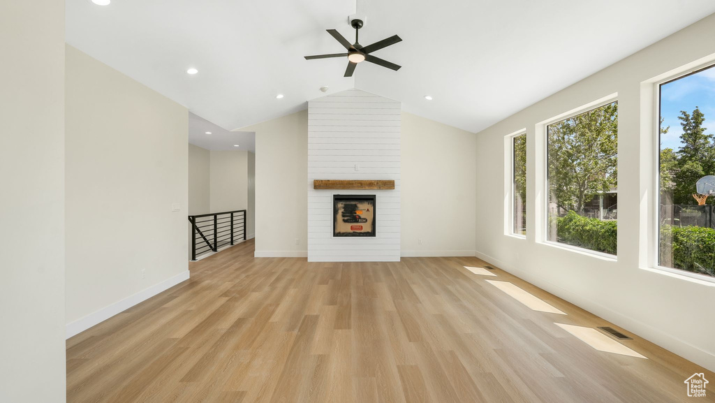 Unfurnished living room with light wood-style floors, a ceiling fan, a large fireplace, recessed lighting, and vaulted ceiling