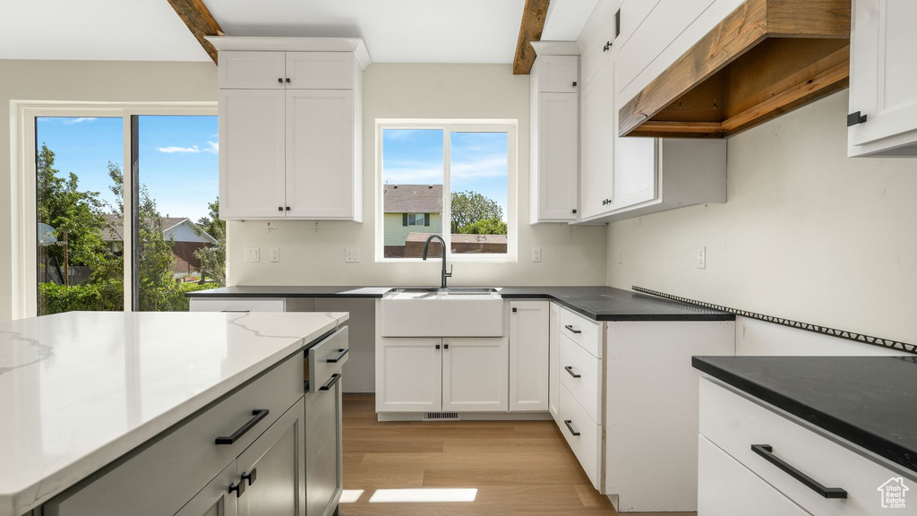 Kitchen featuring premium range hood, light wood-type flooring, and white cabinets