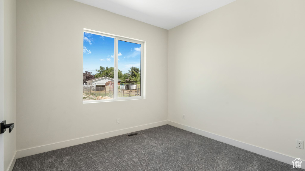 Unfurnished room with dark carpet and baseboards