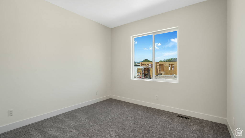 Empty room with dark colored carpet and baseboards