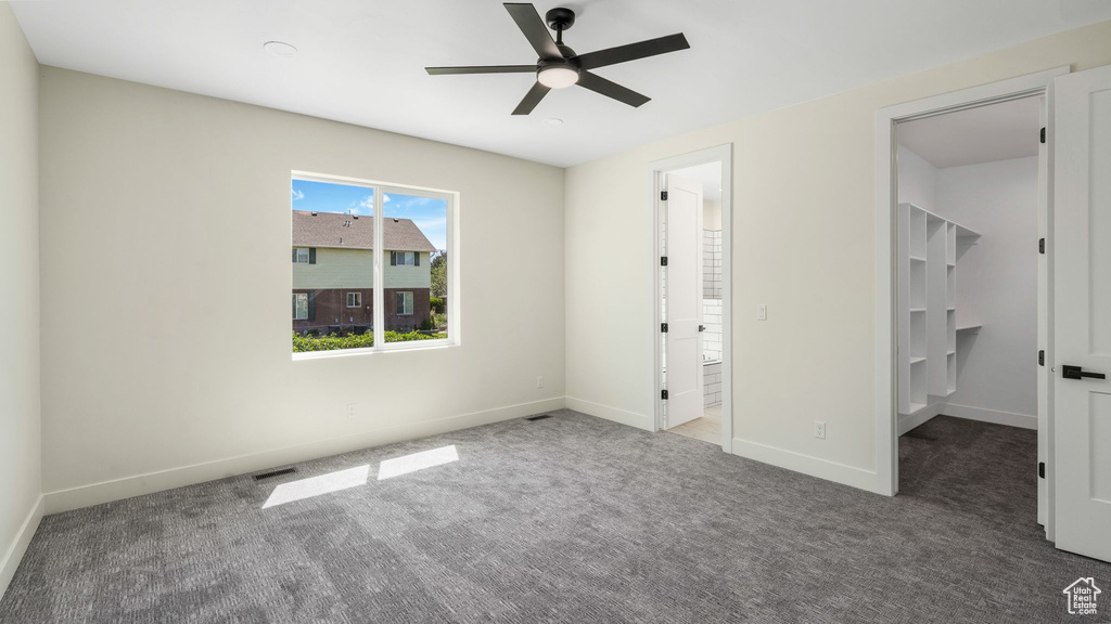 Unfurnished bedroom featuring carpet flooring, a spacious closet, and a ceiling fan